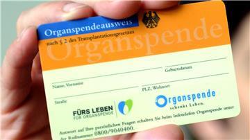 Eine Frau hält einen Organspendeausweis in der Hand.