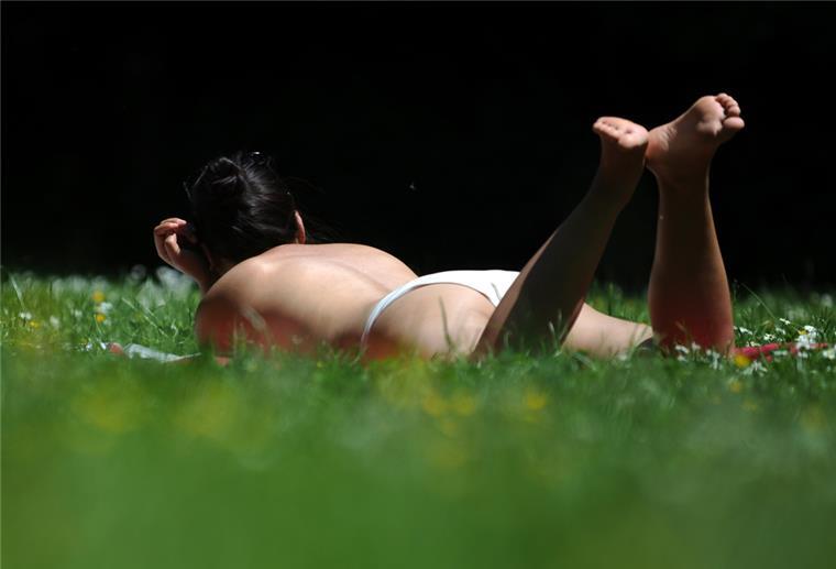 Eine Frau liegt auf einer Wiese in München (Bayern) in der Sonne.