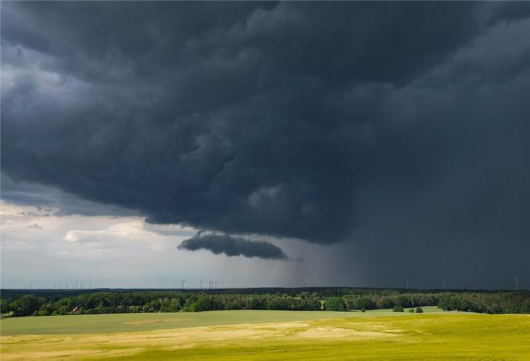 Eine Gewitterzelle mit dunklen Wolken zieht über die Landschaft.