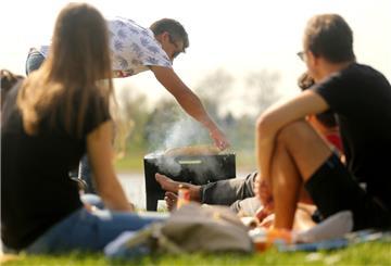 Eine Gruppe junger Leute grillt an einem Sommerabend gemeinsam am Wasser: „Hygge“ steht im Dänischen für die kleinen Freuden im Alltag, die die Lebensqualität erhöhen.