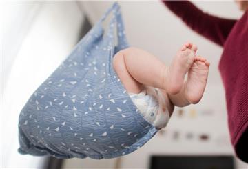 Eine Hebamme wiegt im Rahmen der Nachsorge ein Baby.