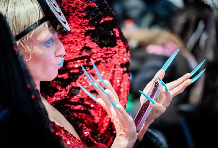 Eine Herausforderung: Ein Model schaut im Backstagebereich vor der „Glück“-Show aufs Handy.
