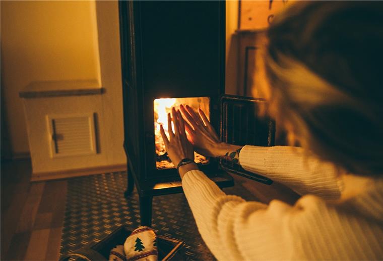 Kuschelige Zeiten an nasskalten Tagen Frau wärmt sich ihre Hände am Kamin