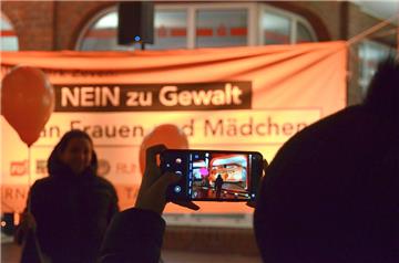 Eine junge Frau fotografiert nahe dem Rathaus in Zeven ein Banner, auf dem Gewalt an Frauen und Mädchen eine Absage erteilt wird. 