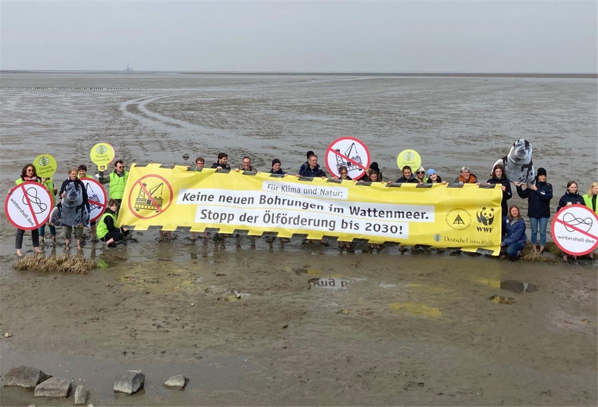Eine klare Forderung: "Keine neuen Bohrungen im Wattenmeer. Stopp der Ölförderung bis 2030!". Im Hintergrund ist am Horizont die Bohrplattform Mittelplate zu sehen.