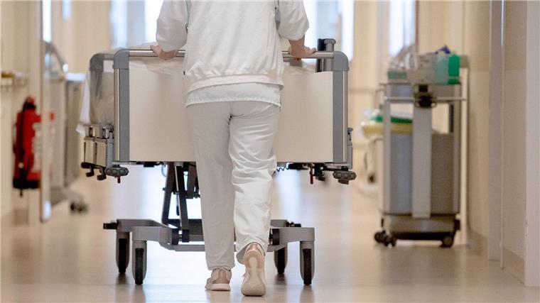 Eine Krankenpflegerin schiebt ein Bett durch einen Flur.