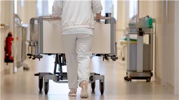 Eine Krankenpflegerin schiebt ein Bett durch einen Flur.