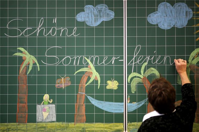 Eine Lehrerin schreibt „Schöne Sommerferien“ an eine Tafel. Wenn es Ende Juni wieder soweit ist, dann sind die Kinder in der Samtgemeinde Tarmstedt offenbar gut versorgt. Jedenfalls scheinen Eltern nicht auf eine Ferienbetreuung angewiesen zu sein. Lediglich ein Kind wurde bisher angemeldet.  