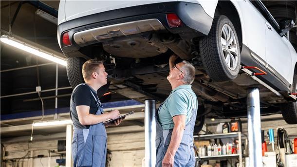 Zwei Männer in einer Autowerkstatt unter einem Auto 