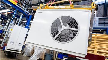 Eine Luft-Wasser-Wärmepumpe hängt in einer Werkshalle der Firma „Stiebel Eltron“ an einem Kran.