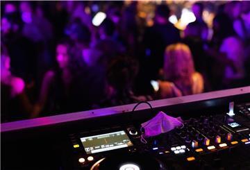 Eine Maske liegt auf dem Mischpult, vor dem Menschen tanzen im Club. Über die Weihanchtstage werden diese in Niedersachsen geschlossen bleiben.