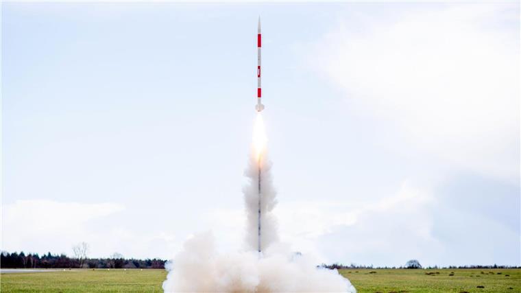 Eine mit mehreren Minisatelliten bestückte Rakete startet 2023 von einer Wiese auf dem Flugplatz.