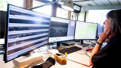 Eine Mitarbeiterin der Waldbrandzentrale Lüneburg sitzt vor Bildschirmen und schaut sich Kamerabilder an.