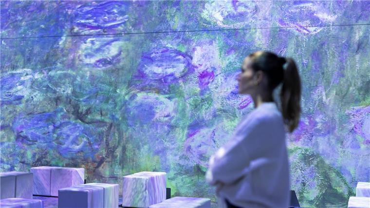 Eine Mitarbeiterin steht in der multimedialen Ausstellung „Monets Garten“.