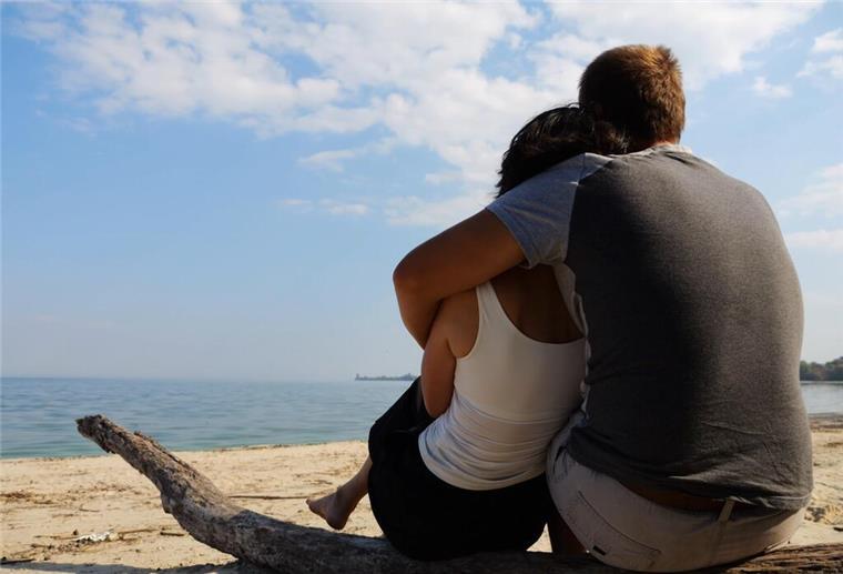 Lebensgroß, liebevoll, laminiert – so basteln sich Frauen ihren Traummann! Ein Paar sitzt eng umschlungen an einem Strand und schaut aufs Meer. Eine neue Methode wirbelt die Partnersuche durcheinander: Frauen visualisieren ihren Wunschpartner auf einem lebensgroßen Foto – und ziehen so Mr. Perfect in ihr Leben.