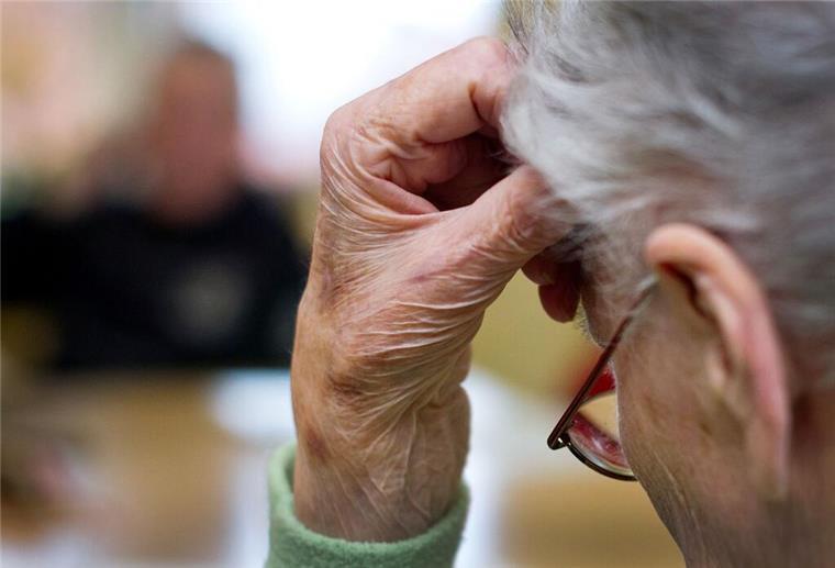 Eine alte und demenzkranke Frau sitzt in einem Pflegeheim.