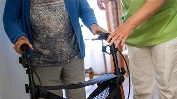 Eine Pflegefachkraft hilft einer Bewohnerin in einem Seniorenheim mit ihrem Rollator.