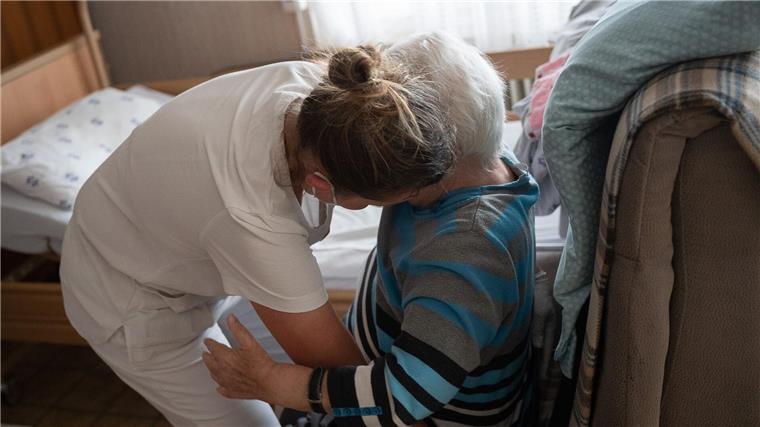 Eine Pflegefachkraft hilft in der ambulanten Pflege einer Frau beim Umsetzen.