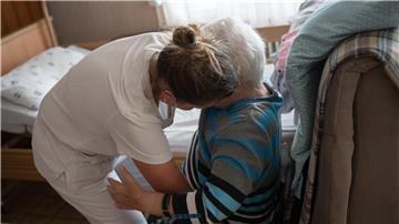 Eine Pflegefachkraft hilft in der ambulanten Pflege einer Frau beim Umsetzen.