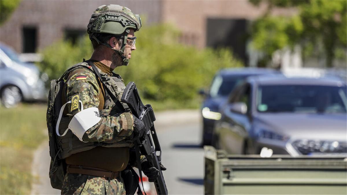 Übung der Marineflieger sorgt für Verkehrsbeeinträchtigung Ein Bundeswehrsoldat in Tarnuniform und Schutzhelm steht mit Gewehr an einer Straße. Im Hintergrund warten Autos vor einer Kontrollstelle.