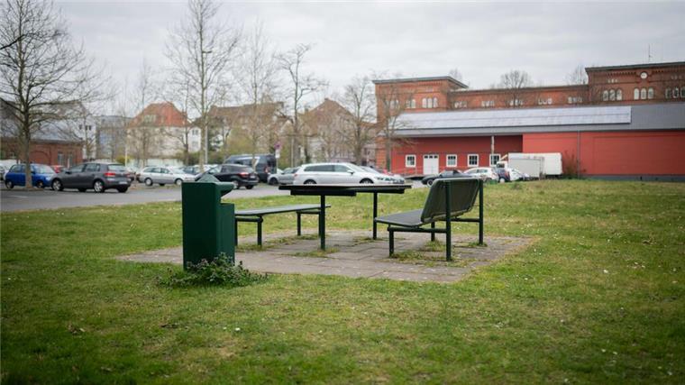 Großbaustelle am Stadthaus 5: Einschränkungen bis zum Sommer Im Vordergrund Rasen sowie zwei Bänke und ein Tisch, im Hintergrund ein mit Pkw belegter Parkplatz
