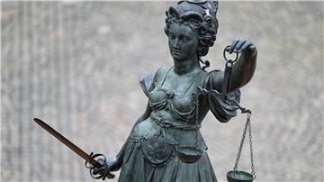 Eine Statue der Justitia hält eine Waage und ein Schwert in der Hand.