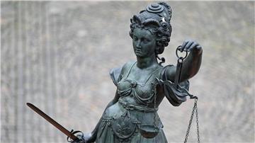 Eine Statue der Justitia hält eine Waage und ein Schwert in der Hand.