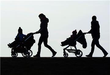 Zwei Mütter schieben Kinderwagen eine Landstraße entlang.