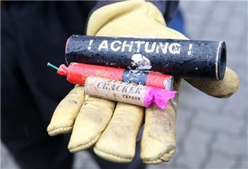 Eine behandschuhte Hand hält mehrere Feuerwerkskörper in die Kamera