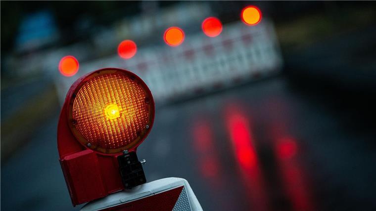 Eine Warnleuchte steht an einem abgesperrten Bereich auf einer Straße.