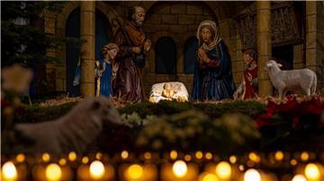 Eine Weihnachtskrippe steht im Osnabrücker Dom hinter brennenden Kerzen.