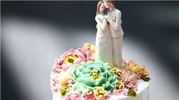 Eine Figur, die einen Mann und eine Frau darstellt, steht auf einer Hochzeitstorte.