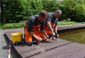 Zwei Männer legen einen neuen Steg am Brunnen in Bad Bederkesa an.