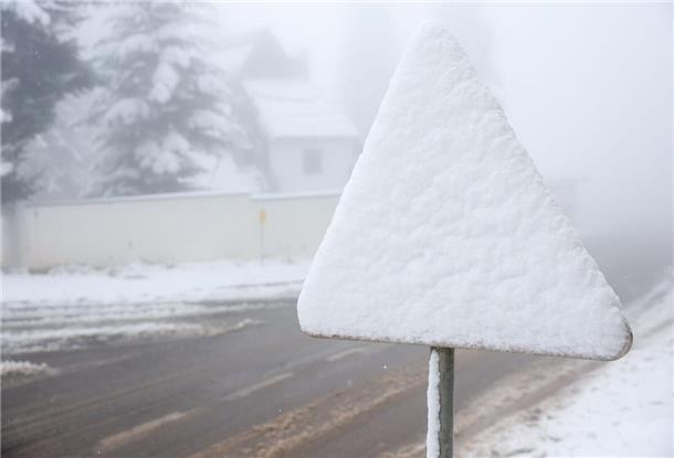 Ein Straßenschild ist während eines unerwarteten Schneefalls auf dem Berg Jahorina in der Nähe von Sarajevo mit Schnee bedeckt.