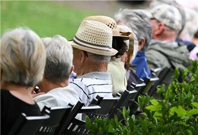 Symbolbild für jüngere Rentner häufig noch beruflich aktiv: Senioren sitzen auf Stühlen und Bänken in einem Park.