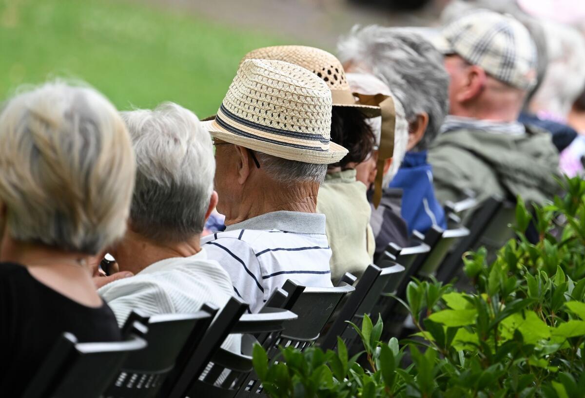 Symbolbild für jüngere Rentner häufig noch beruflich aktiv: Senioren sitzen auf Stühlen und Bänken in einem Park.