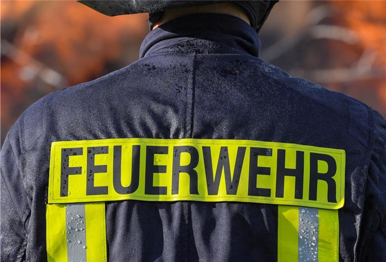 Ein Mitglied der Freiwilligen Feuerwehr Sieversdorf sichert ein großes Lagerfeuer ab.