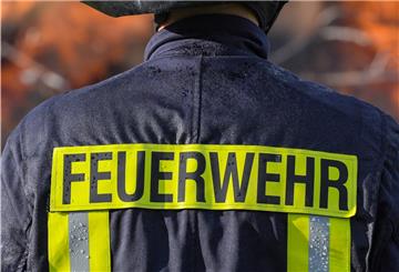Ein Mitglied der Freiwilligen Feuerwehr Sieversdorf sichert ein großes Lagerfeuer ab.