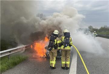 Einsatzkräfte der Feuerwehr löschen ein brennendes Auto. 