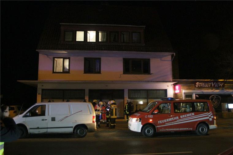 Einsatzkräfte des Rettungsdienstes und der Feuerwehr stehen vor dem Haus in Bremen-Farge, in dem bei einem Grillabend im Keller acht Menschen teils lebensgefährlich verletzt worden sind, 