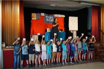 „Ella in der Schule“, ergeben die Buchstaben, die die Jungen und Mädchen der Grundschule Abbehausen nach oben halten. Das war der Titel eines der sechs Bücher, die  Tina Kemnitz den Grundschülern vorstellte. 