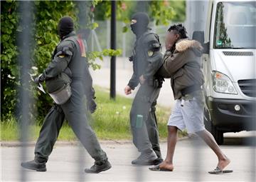 Ellwangen: In der Landeserstaufnahmeeinrichtung für Flüchtlinge (LEA) wird ein Mann von maskierten Polizisten eskortiert.

 