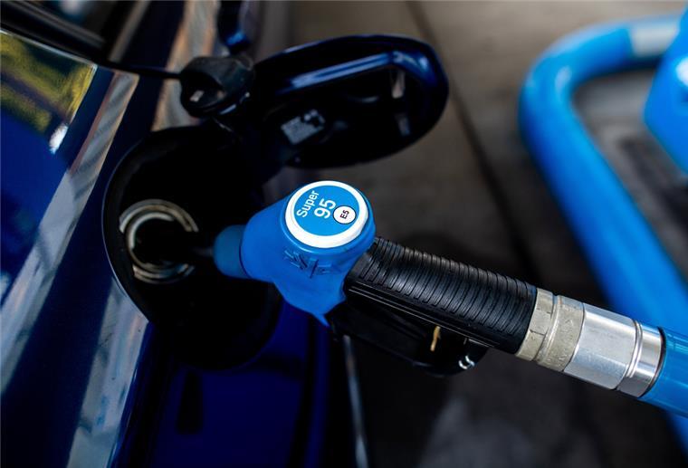 Eine Zapfpistole mit der Aufschrift "Super 95" steckt an einer Tankstelle in der Tanköffnung eines Fahrzeugs.