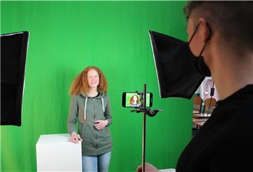 Englischlehrerin Marleena Schulz wird vom ehemaligen Schüler Tarran Durham vor dem "Greenscreen" gefilmt. Am Computer wird der Hintergrund später geändert.