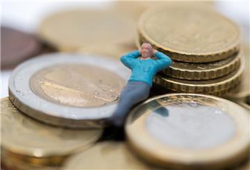 Die Figur einer Person liegt auf Euro-Münzen.