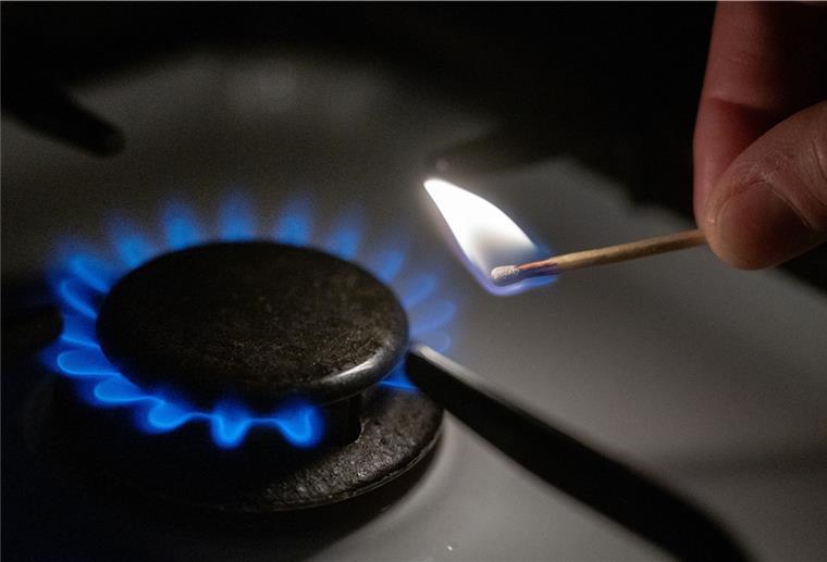Eine Gasflamme wird auf einem Küchenherd mit einem Streichholz entzündet. 
