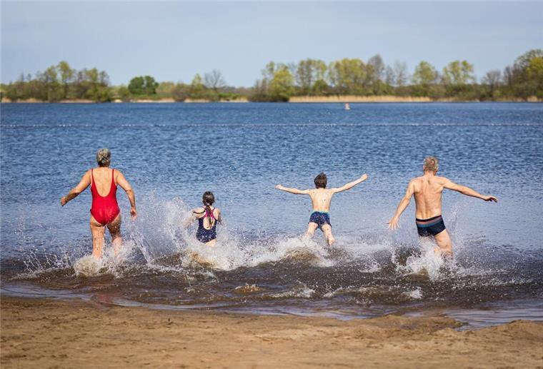 ARCHIV - Eine Familie läuft bei sonnigem Wetter in den Hufeisensee in der Region Hannover. Foto: Moritz Frankenberg/dpa