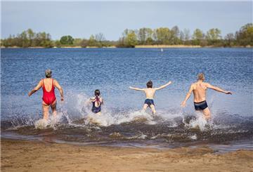 ARCHIV - Eine Familie läuft bei sonnigem Wetter in den Hufeisensee in der Region Hannover. Foto: Moritz Frankenberg/dpa