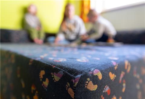 Kinder spielen auf einer Sitzecke. 