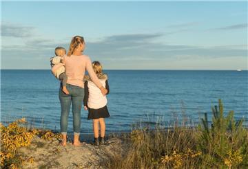 Eine Mutter mit zwei Kindern am Meer. 